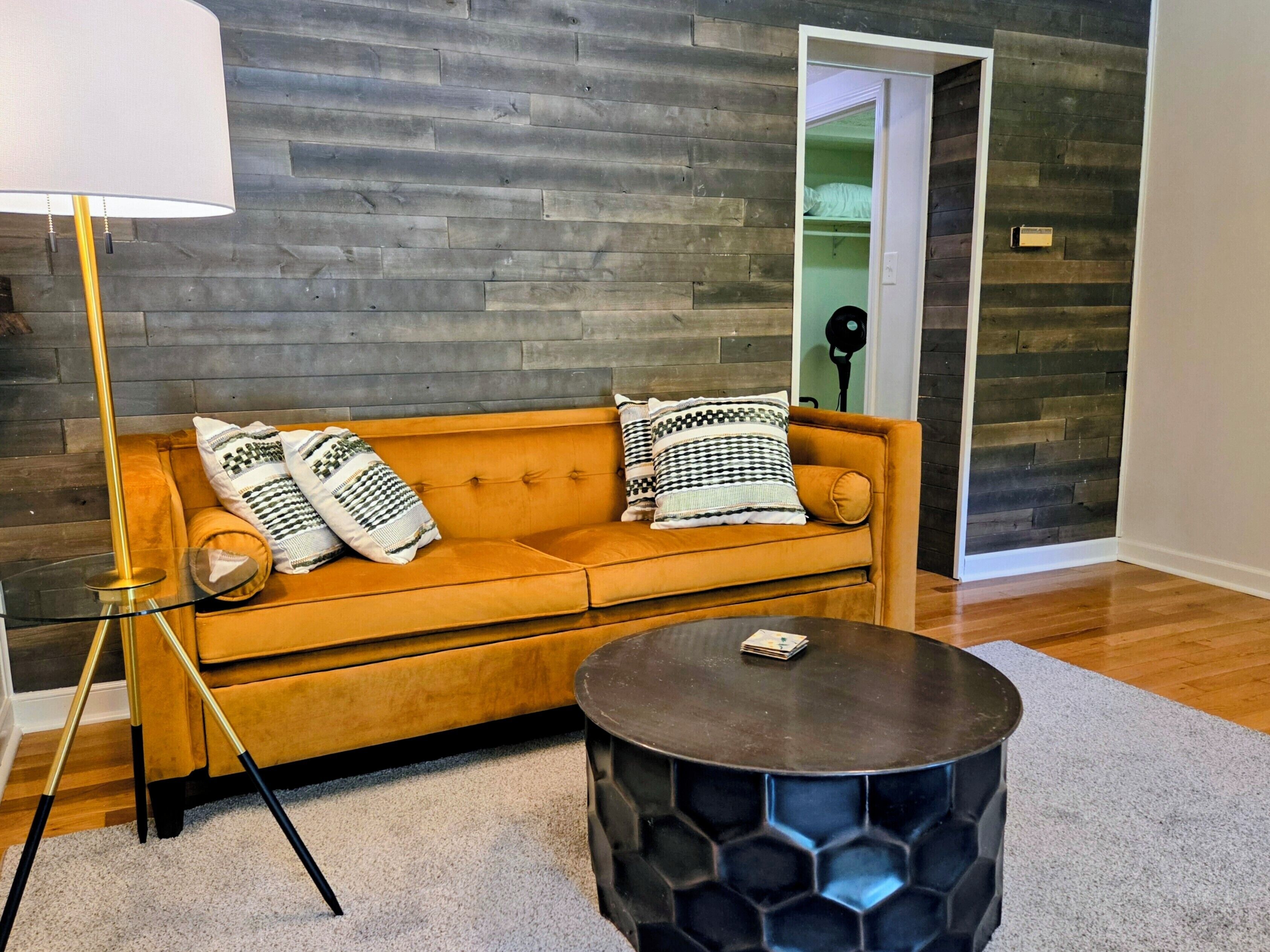 A modern living room with a sofa, a lamp, and a round table.