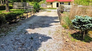 A gravel path leading to a building with a red roof, surrounded by trees and greenery. - Escape the hustle and reconnect with nature at Outpost, your stay tucked along the borders of Shawnee State Forest. Whether you're seeking a solo retreat, a romantic getaway, or a  weekend with friends, this spot offers a blend of woods & comfort. (West Portstmouth)