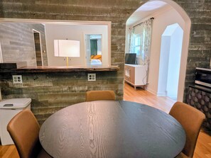 Un coin repas avec une table ronde, des chaises et un mur décoratif en bois.