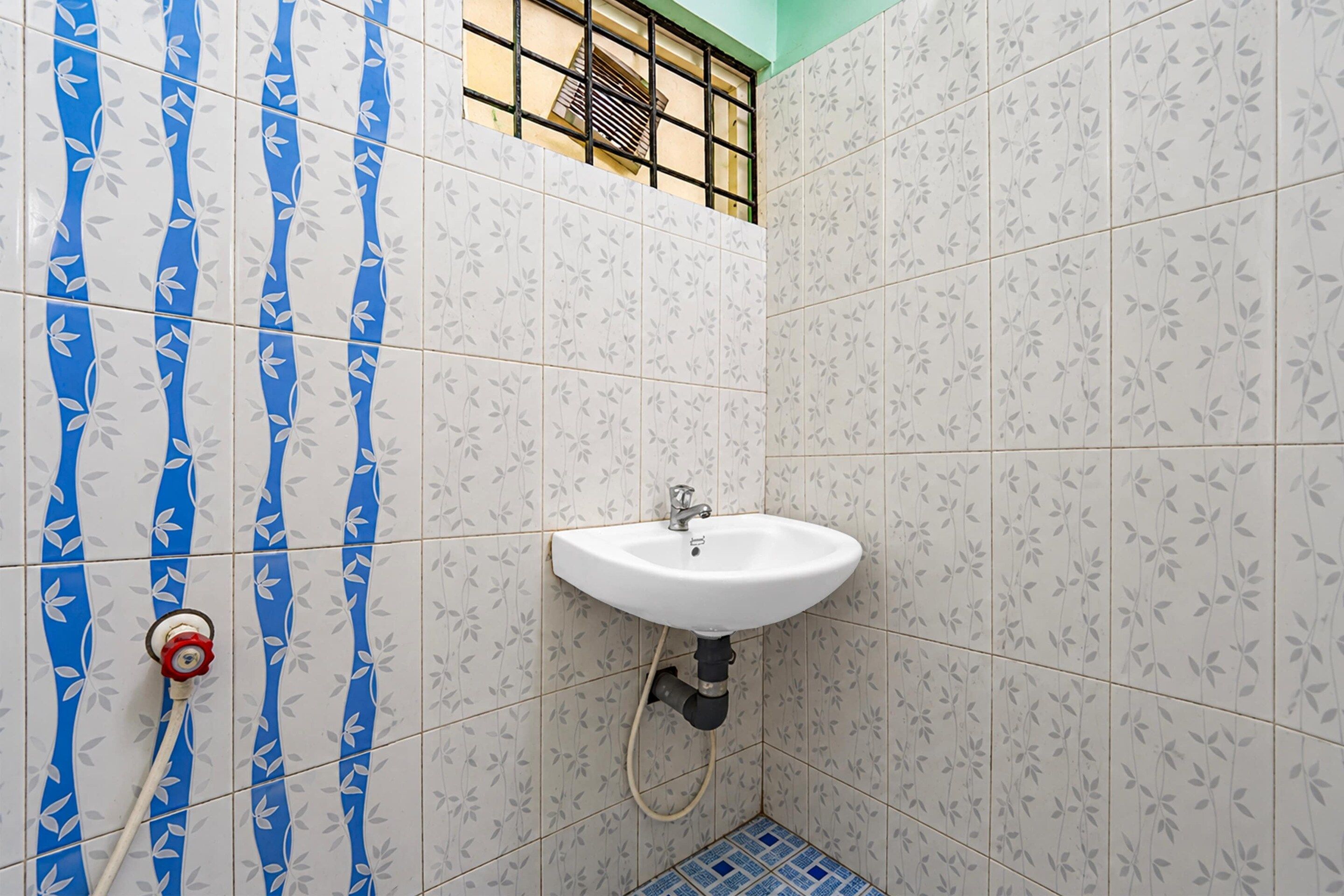 A bathroom with a white sink, a shower, and blue and white patterned tiles.