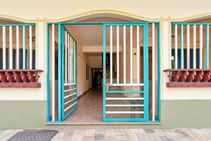 A building entrance with a gated door, a staircase leading inside, and a visible hallway.