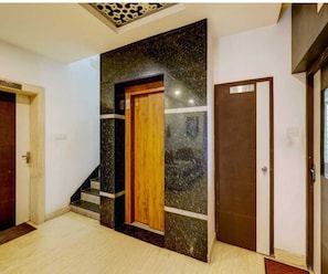 A hallway with a wooden door labeled 'TOILET' and a marble wall.