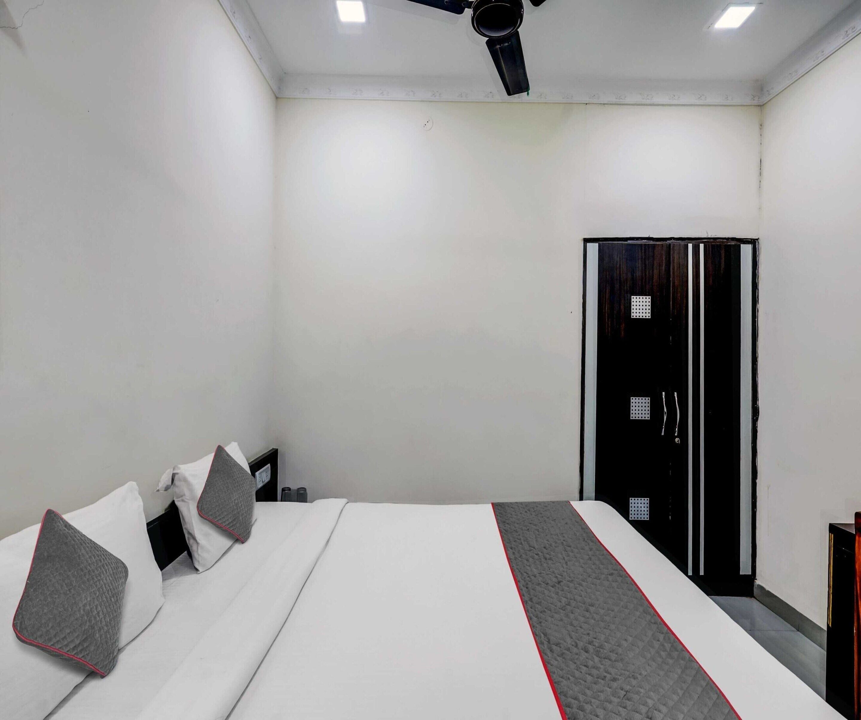 A hotel room with a bed, pillows, a wardrobe, and a ceiling fan.
