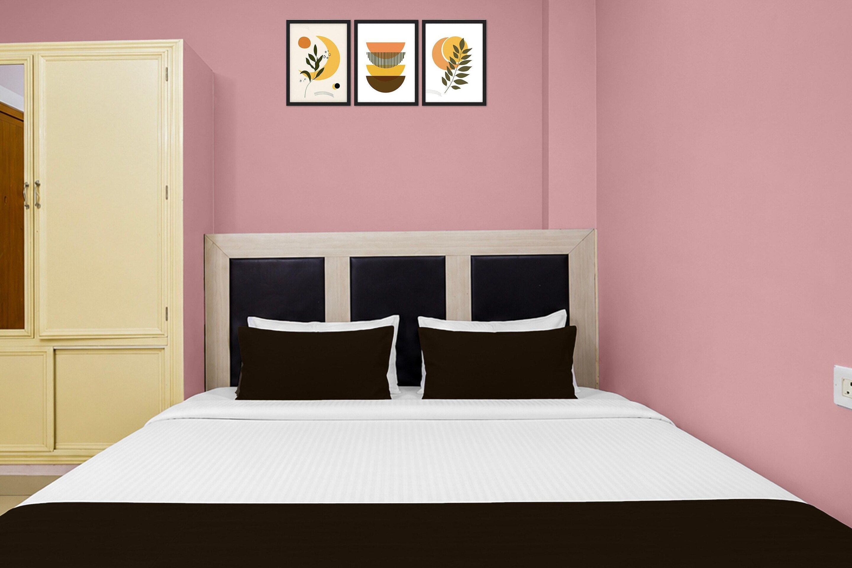 Une chambre à coucher comprenant un lit, une armoire et trois œuvres d’art encadrées accrochées au mur.