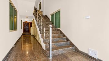 A polished marble staircase with a handrail, leading to a landing with a door.