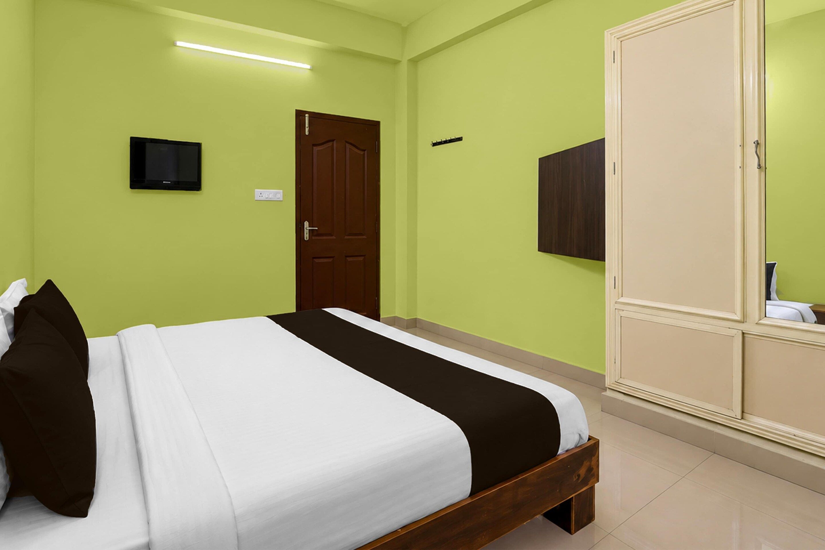 A hotel room with a bed, a wardrobe, a television, and a door.