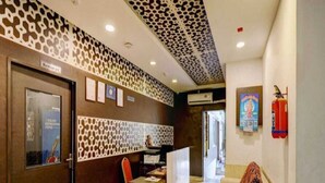 A reception area with a patterned wall, a reception desk, a chair, a sofa, and a fire extinguisher.