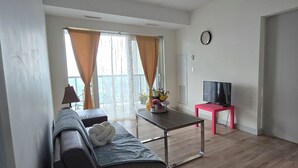 A living room with a sofa, a coffee table, a TV on a stand, and a window with curtains. - Penthouse in the Sky (Waterloo)