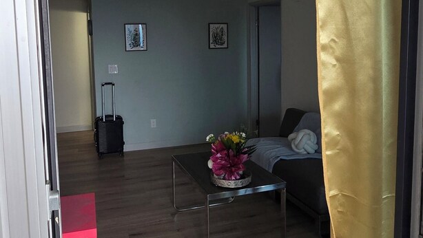 An open door to a living room with a sofa, a coffee table, and a red chair. - Penthouse in the Sky (Waterloo)