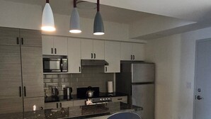 A modern kitchen with a central island, two bar stools, and pendant lighting. - Penthouse in the Sky (Waterloo)