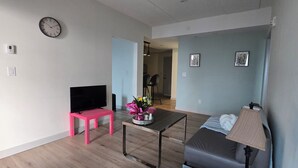 A living room with a flat-screen TV, a pink chair, a coffee table, a sofa, and a lamp. - Penthouse in the Sky (Waterloo)