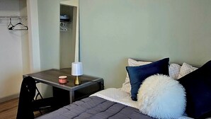 A bedroom with a bed, a desk, a chair, a mirror, and a hanging coat rack. - Penthouse in the Sky (Waterloo)