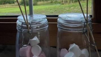 Two glass jars with metal clasps on a wooden surface, with a view of a green landscape through a window.