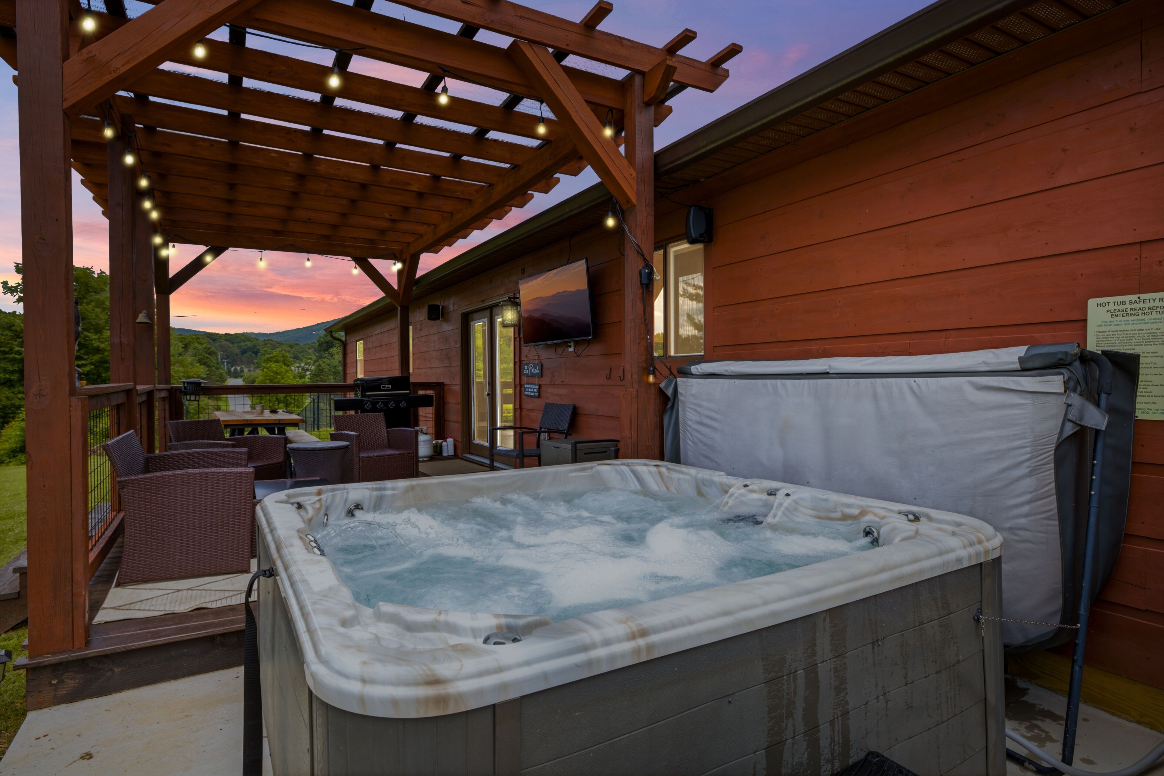 Een hottub onder een houten pergola, met uitzicht op een bergachtig landschap.