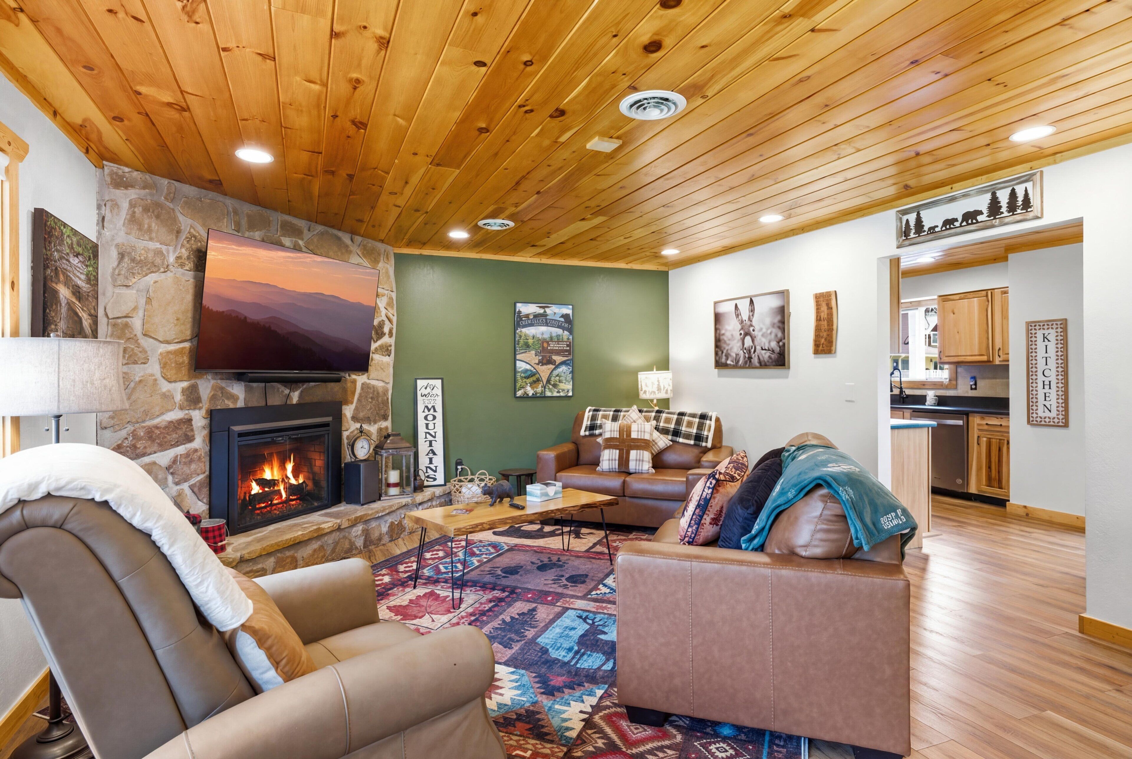 Una sala acogedora con chimenea de piedra, televisor y pared verde.