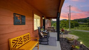Puinen ulkoseinä, jossa on penkki ja tuoleja, kyltti, jossa lukee ”Great Smoky Mountains”, sekä näkymä tielle ja vehreään maisemaan.