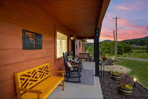 Fachada de madera con un banco y sillas, un letrero que dice 'Great Smoky Mountains' y vistas a una carretera y vegetación.