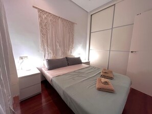 Ein Schlafzimmer mit Bett, Nachttischen, einem Kleiderschrank und einem Fenster mit Vorhängen.