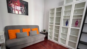 A living room with a grey sofa, orange and grey cushions, a white cabinet with glass doors, and a framed picture on the wall. - Apartment in downtown Valencia, close to everything (València)