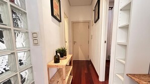 A hallway with a wooden bench, a potted plant, and a door at the end. - Apartment in downtown Valencia, close to everything (València)