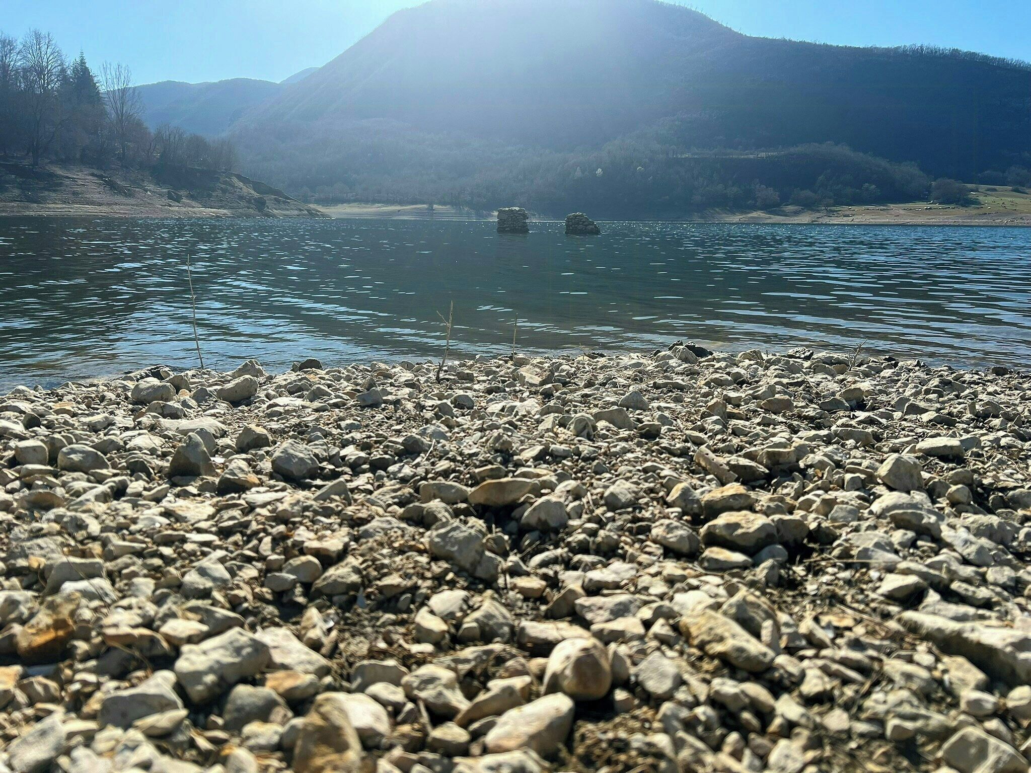 Eine felsige Küste mit einem Berg im Hintergrund.