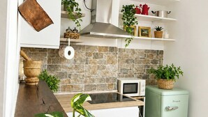 A modern kitchen with a stone backsplash, white cabinetry, and a vintage-style refrigerator.