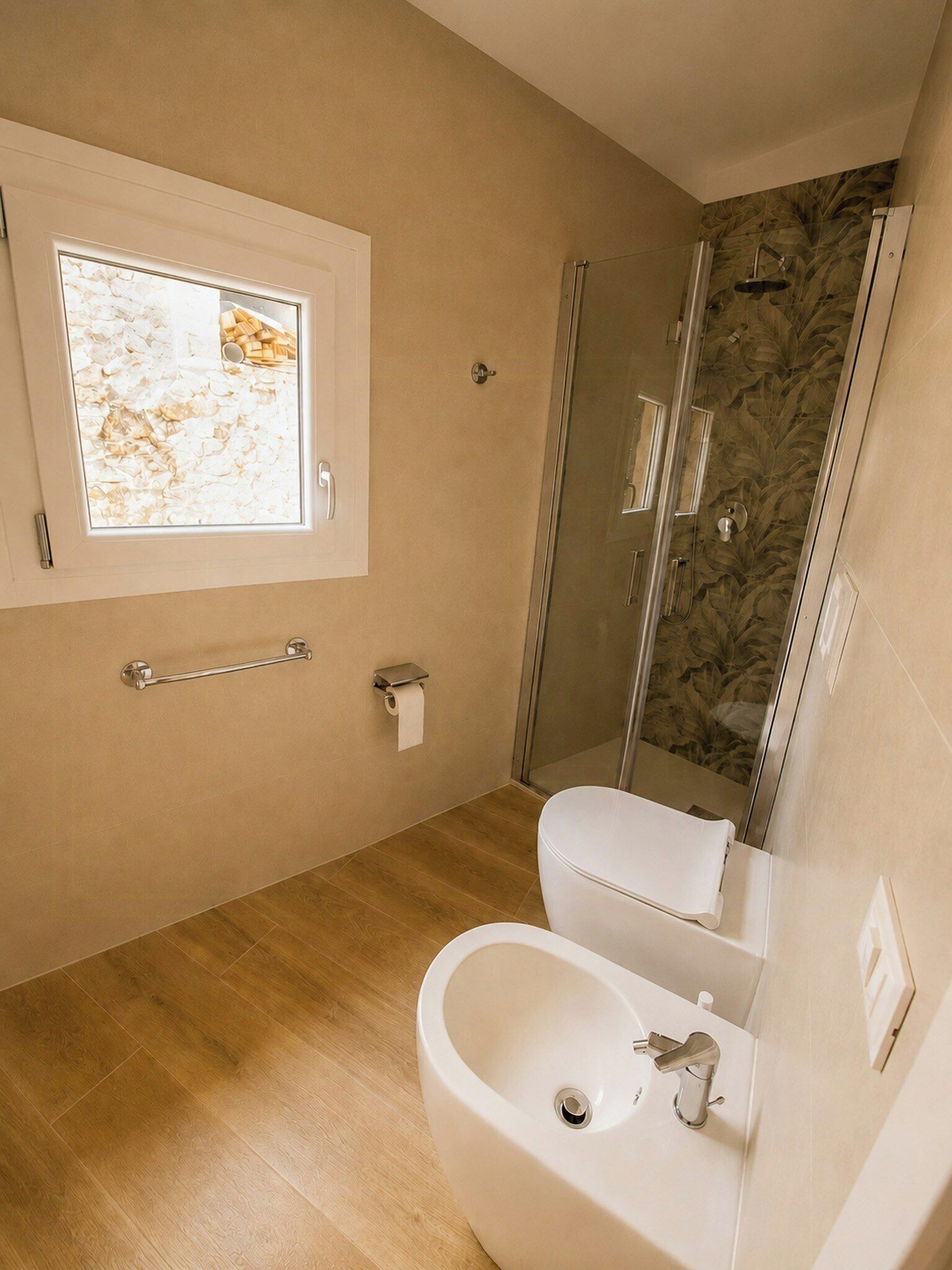 Une salle de bain équipée de toilettes, d’un bidet et d’une douche à parois de verre.