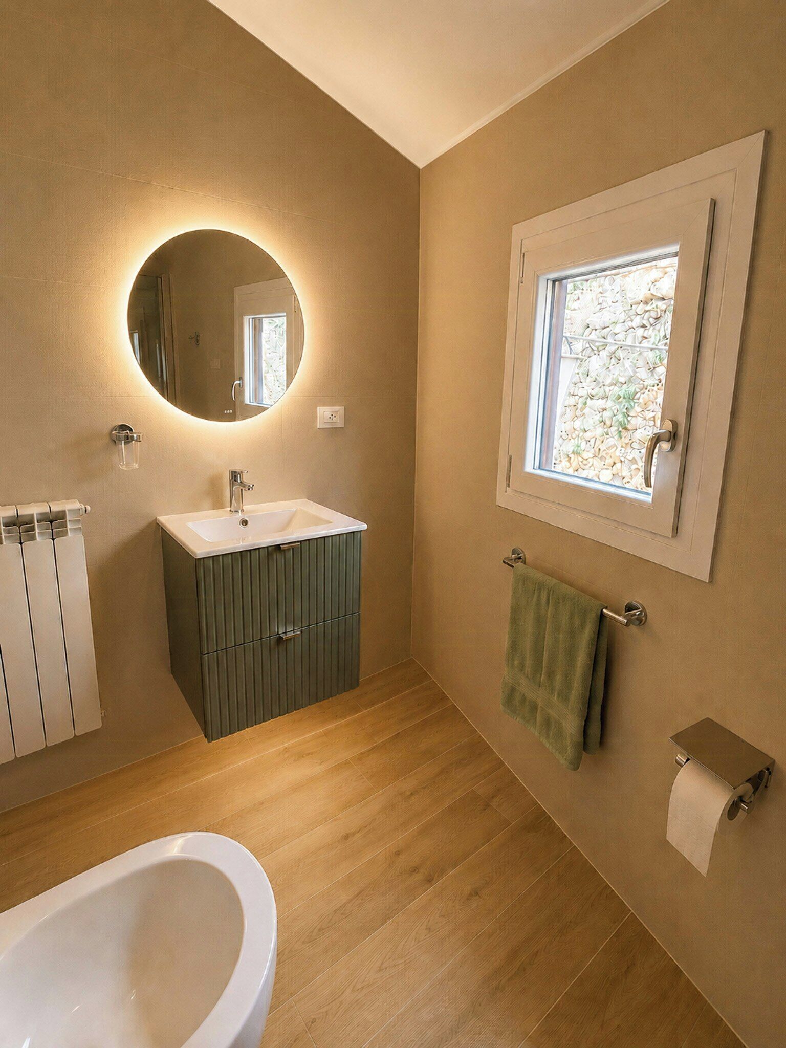 Un baño con bañera, lavabo, espejo, ventana y toallero.