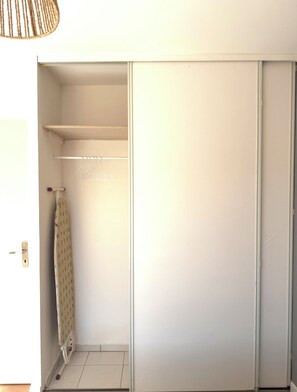 A room with a sliding closet door, a towel rack, and a hanging clothes rack. - L'Île Rousse - Two-bedroom apartment with a terrace offering views of the sea and mountains - 8-minute walk to the beach (L'Île-Rousse)