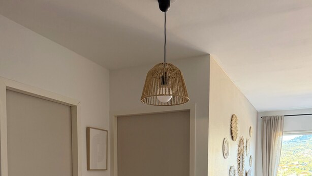 Ein Schlafzimmer mit einem Bett, einer Hängelampe, einer Tür und einer Wand mit Wandplatten.