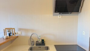 Eine moderne Küche mit Spüle aus Edelstahl, integriertem Herd, dunklen Holzschränken und einem an der Wand montierten Fernseher.