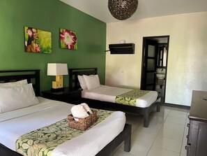 A hotel room with two beds, a nightstand with a lamp, a wall-mounted shelf, and a door leading to a bathroom. - Puerto Del Sol Beach Resort and Hotel Club Bolinao (Bolinao)