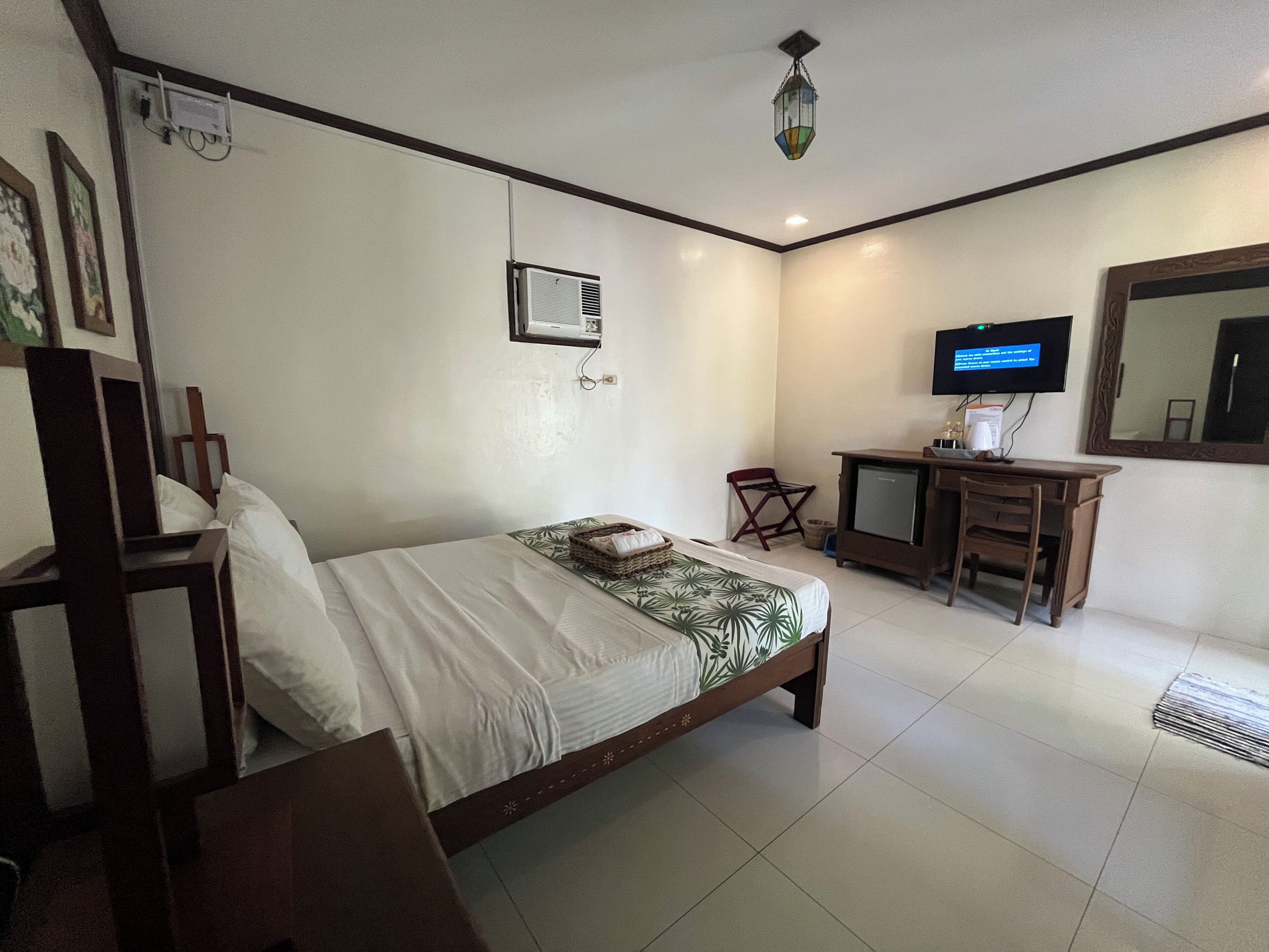 A hotel room with a bed, a desk, a television, and a mirror.
