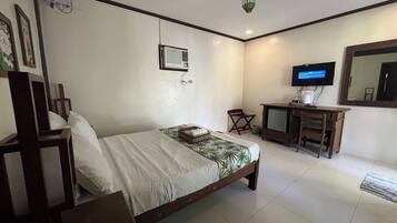 A hotel room with a bed, a desk, a television, and a mirror.