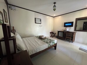Une chambre d’hôtel avec un lit, un bureau, une télévision et un miroir.