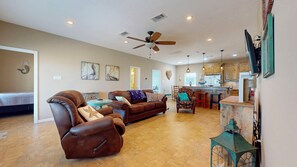 A spacious living room with a brown leather sofa, a recliner, and a dining area with a kitchen in the background. - Turtlely Relaxed: 3  BR, 2  BA House in Crystal Beach, Sleeps 10 (Crystal Beach)