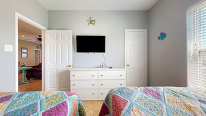 A bedroom with a bed, dresser, and a television on the wall. - Turtlely Relaxed: 3  BR, 2  BA House in Crystal Beach, Sleeps 10 (Crystal Beach)