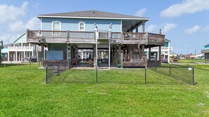 A two-story house with a balcony and a covered porch area. - Turtlely Relaxed: 3  BR, 2  BA House in Crystal Beach, Sleeps 10 (Crystal Beach)