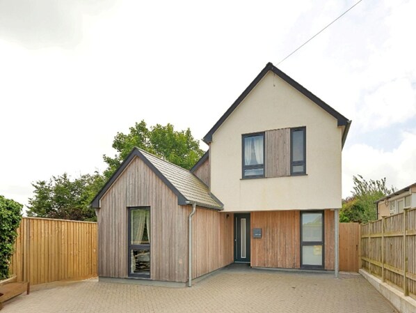 A two-story house with a wooden exterior and a small attached garage. - Cozy Oasis Near Town Center (Bude)