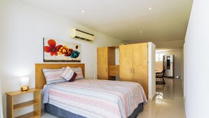 Un dormitorio con cama, mesita de noche, armario y un cuadro en la pared.