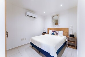 Ein Schlafzimmer mit einem Bett, Nachttischen, einem Spiegel und einer Klimaanlage.