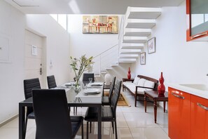 A modern dining area with a glass table, black chairs, and a staircase leading to a loft. - Main Level 2BR | Oceanview, Pool & Beach (Huatulco)