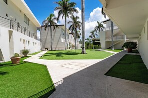 A modern building with a courtyard, palm trees, and a clear sky. - Main Level 2BR | Oceanview, Pool & Beach (Huatulco)