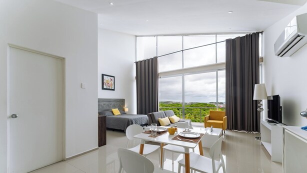 Uma sala de estar moderna com um sofá, uma mesa de jantar com cadeiras, uma televisão e uma janela grande com cortinas.
