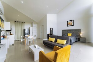 Ein modernes Hotelzimmer mit Sofa, Essbereich, Küchenzeile und einem großen Bett.