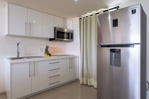 A modern kitchen with white cabinets, a stainless steel refrigerator, a microwave, and a water dispenser.