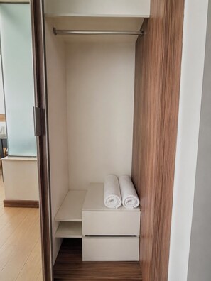 Un closet amplio con puerta de madera, un estante blanco y dos toallas enrolladas.