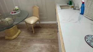 Cocina compacta con comedor, una silla, una mesa de vidrio y un lavamanos.