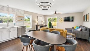 Eine moderne Küche mit Essbereich, einer Couch und einem an der Wand montierten Fernseher.