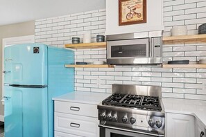 Eine Küche mit einem blauen Kühlschrank, einer Mikrowelle und einem Herd.